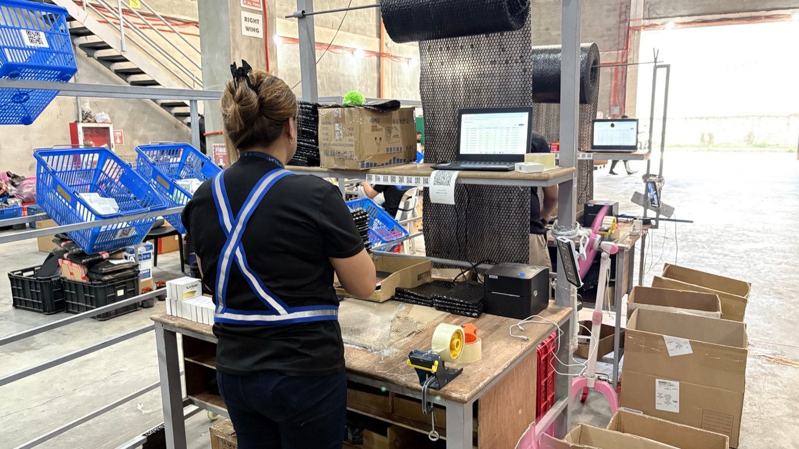 An Inspire operator packing an order at a real packing station with bubble wrap, tape and the Fusion order screen